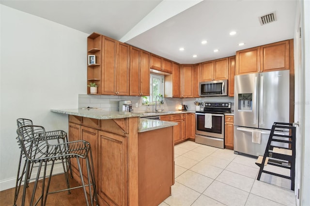 1735 Maryland Ave NE, Saint Petersburg, FL 33703 - kitchen with stainless steel appliances, a peninsula, a sink, brown cabinets, and recessed lighting