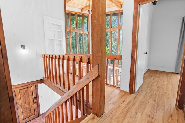 corridor with baseboards, beam ceiling, and wood finished floors