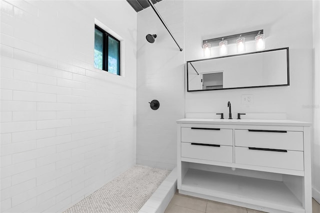 full bath featuring vanity, tile patterned flooring, and tiled shower