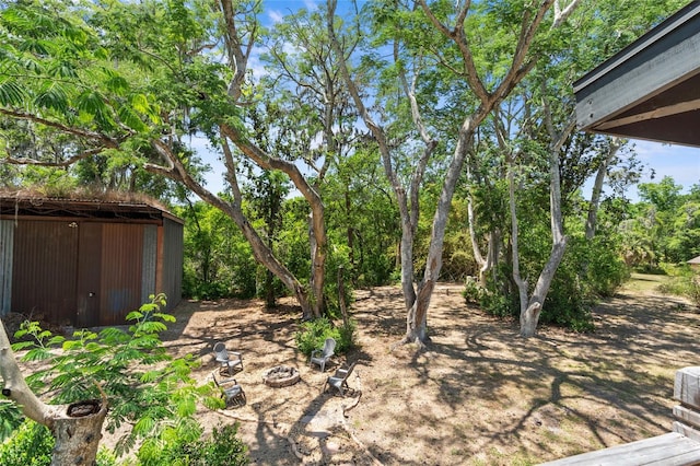 view of yard with a fire pit and an outdoor structure