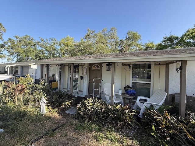 rear view of property with roof with shingles, covered porch, and an attached garage