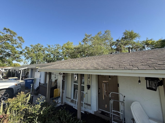 view of front of home featuring a shingled roof and stucco siding