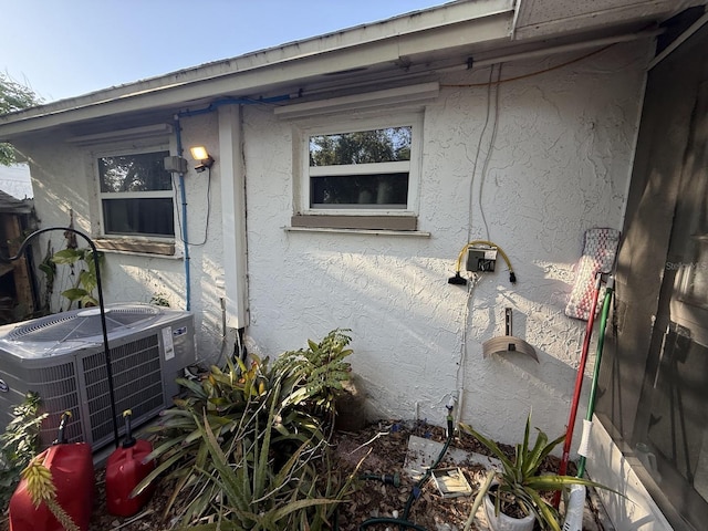 view of side of property with stucco siding and central air condition unit