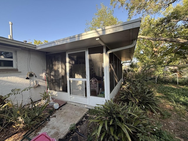 view of property exterior with stucco siding and a sunroom
