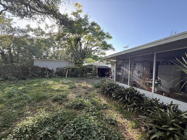 view of yard featuring fence and a sunroom