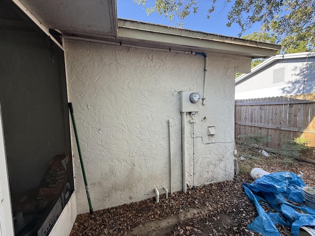 details with stucco siding, electric meter, and fence