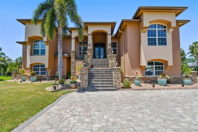 mediterranean / spanish house with a front lawn, stairs, and stucco siding