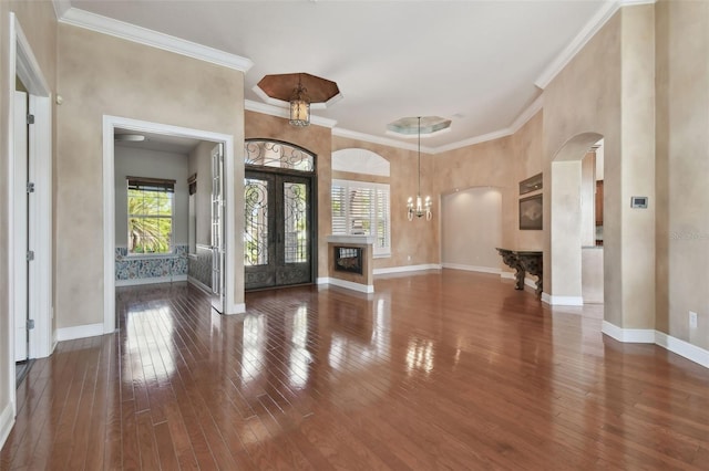 foyer entrance with arched walkways, ornamental molding, baseboards, and hardwood / wood-style flooring