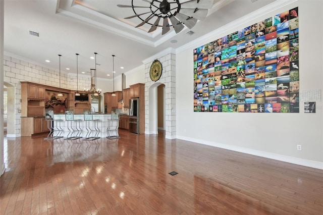 living room featuring arched walkways, ceiling fan with notable chandelier, ornamental molding, recessed lighting, and dark wood-type flooring