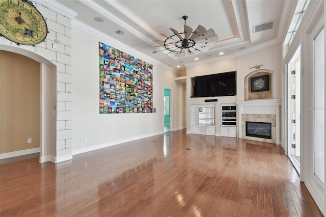 unfurnished living room featuring visible vents, crown molding, wood-type flooring, a glass covered fireplace, and a wealth of natural light