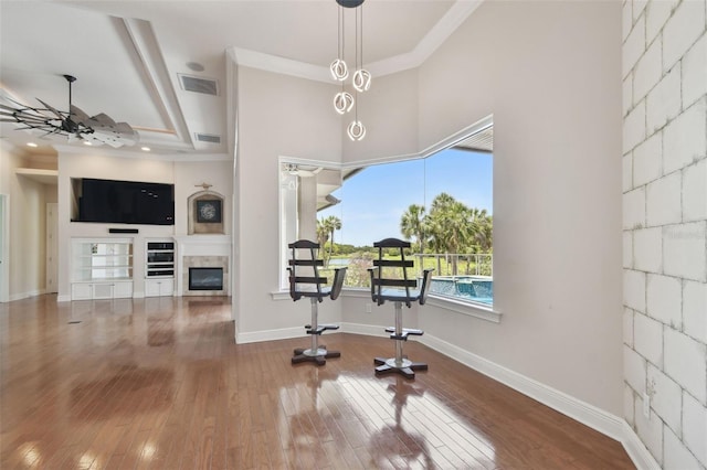 dining room with a ceiling fan, visible vents, a glass covered fireplace, and hardwood / wood-style floors