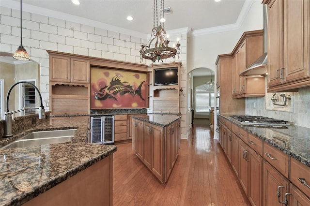 kitchen featuring brown cabinetry, arched walkways, open shelves, a sink, and beverage cooler