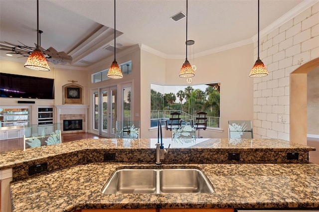 kitchen with a sink, dark stone counters, ornamental molding, and open floor plan