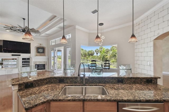 kitchen with a ceiling fan, open floor plan, ornamental molding, and a sink