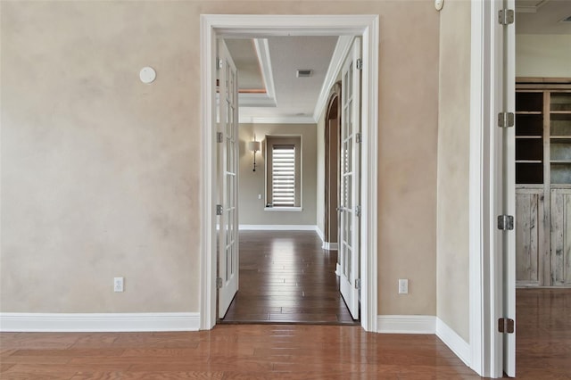 corridor with visible vents, ornamental molding, hardwood / wood-style floors, baseboards, and french doors
