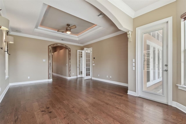 empty room featuring french doors, arched walkways, a ceiling fan, and wood finished floors