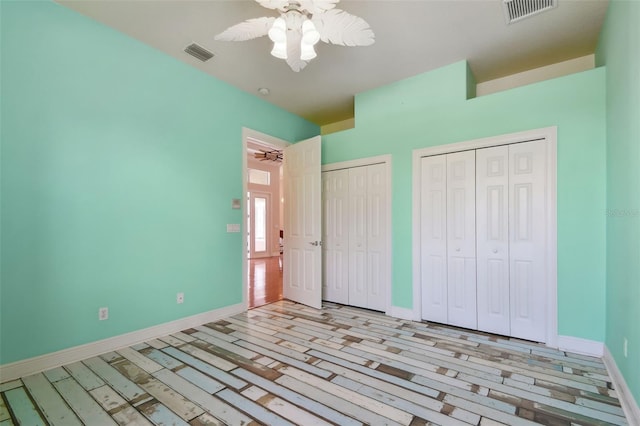 unfurnished bedroom featuring multiple closets, visible vents, and baseboards