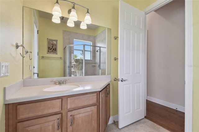 full bath featuring tile patterned flooring, a stall shower, vanity, baseboards, and an inviting chandelier