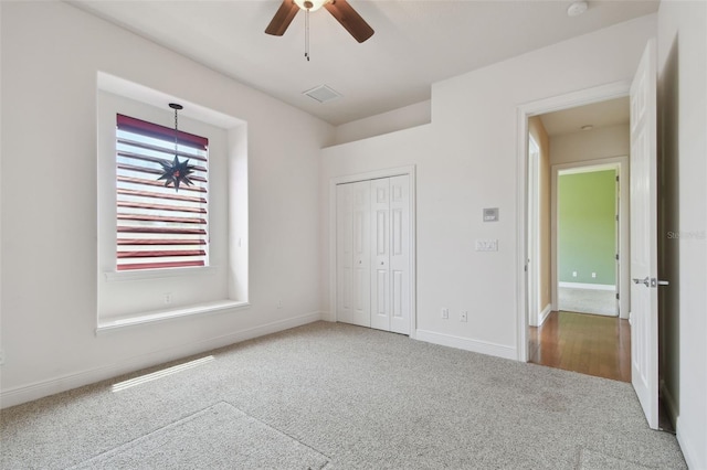 unfurnished bedroom featuring carpet flooring, ceiling fan, baseboards, visible vents, and a closet