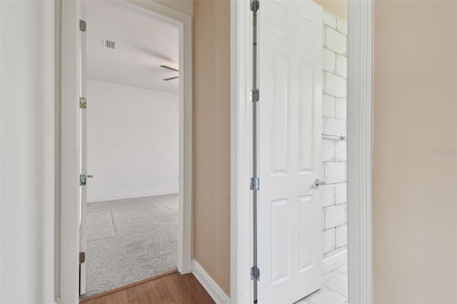 corridor featuring baseboards, visible vents, and wood finished floors