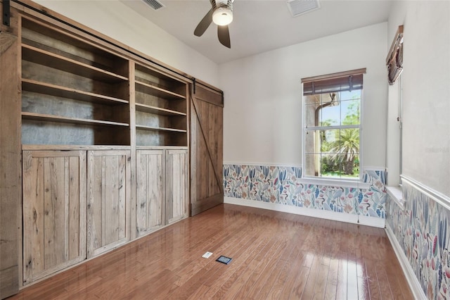 empty room with baseboards, visible vents, wallpapered walls, and a wainscoted wall