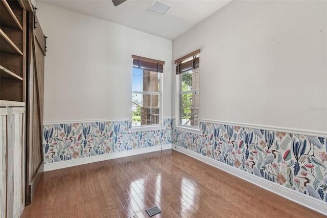 empty room featuring baseboards, visible vents, wainscoting, and hardwood / wood-style floors