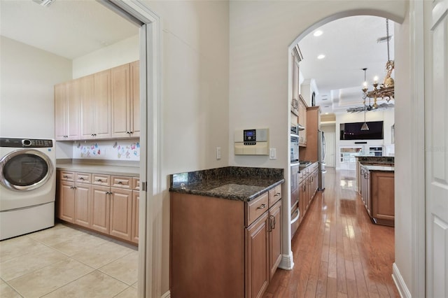 clothes washing area with cabinet space, light wood-style floors, arched walkways, recessed lighting, and washer / dryer