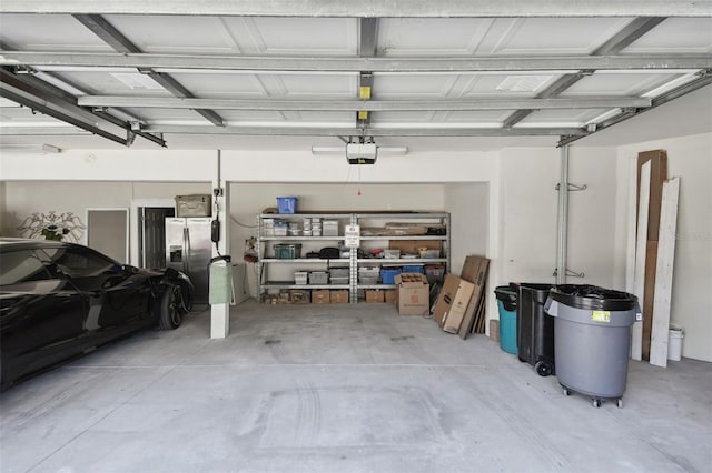 garage featuring a garage door opener and stainless steel refrigerator with ice dispenser