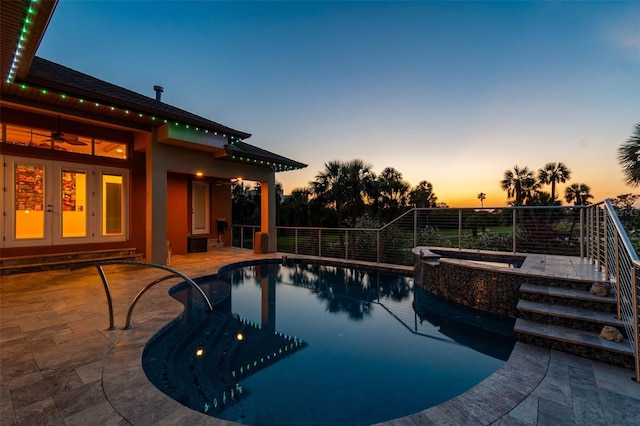 pool at dusk with a patio, a ceiling fan, a pool with connected hot tub, and french doors