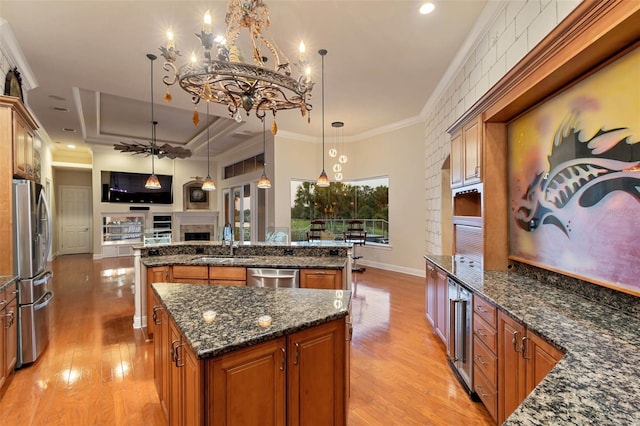 2605 59th St S, Gulfport, FL 33707 - kitchen featuring a sink, a large island with sink, brown cabinets, light wood-style flooring, and appliances with stainless steel finishes