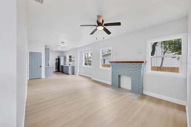 1045 22nd Ave N, Saint Petersburg, FL 33704 - unfurnished living room featuring baseboards, ceiling fan, a brick fireplace, and light wood-style flooring