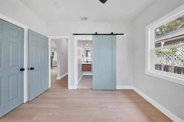 1045 22nd Ave N, Saint Petersburg, FL 33704 - unfurnished bedroom featuring baseboards, visible vents, a barn door, and light wood-style flooring