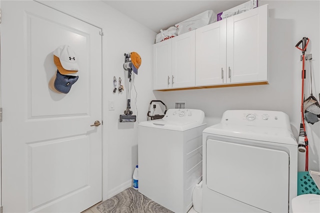 clothes washing area featuring separate washer and dryer and cabinet space