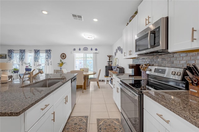 kitchen with a sink, appliances with stainless steel finishes, backsplash, and white cabinetry