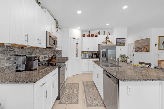 kitchen featuring tasteful backsplash, a sink, light tile patterned floors, stainless steel appliances, and an island with sink