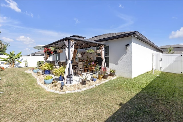 back of property with a gazebo, stucco siding, a yard, and a patio