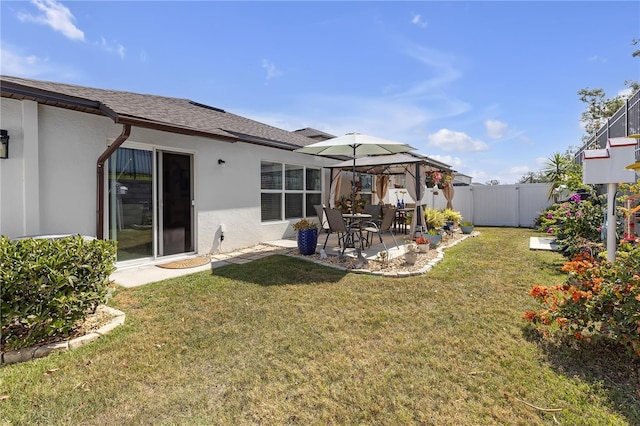 rear view of house with a gazebo, fence, a patio area, and stucco siding