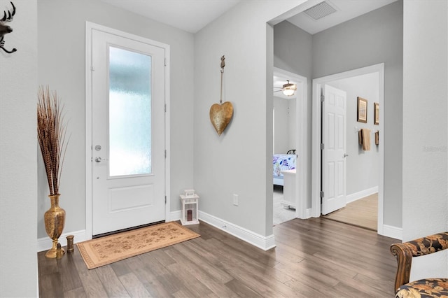 foyer entrance featuring baseboards, visible vents, and wood finished floors