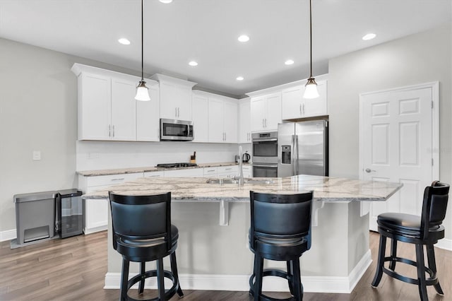 kitchen featuring stainless steel appliances, white cabinetry, a sink, and wood finished floors
