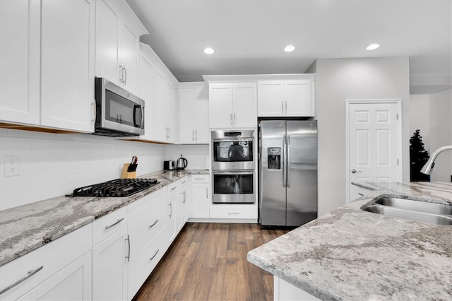 kitchen with white cabinets, tasteful backsplash, a sink, dark wood finished floors, and appliances with stainless steel finishes
