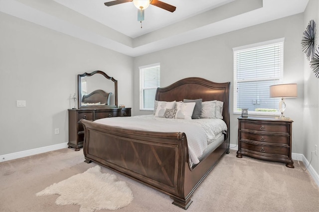 bedroom featuring baseboards, ceiling fan, light carpet, and a raised ceiling