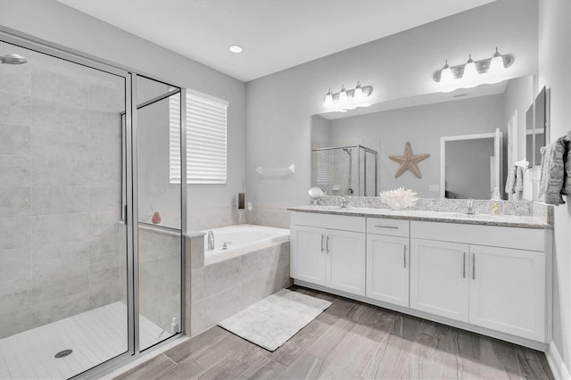 bathroom with double vanity, a sink, a bath, and a shower stall