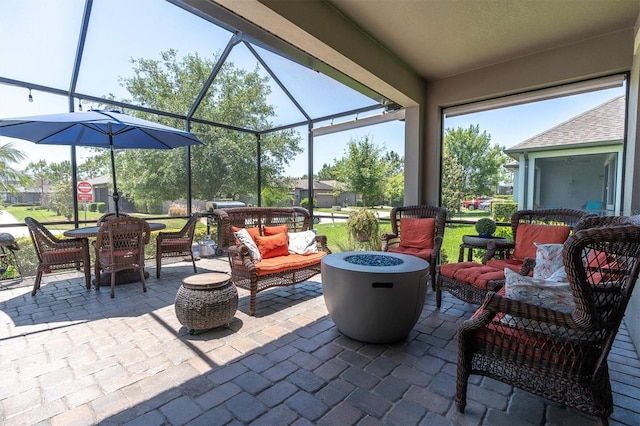 view of patio with a lanai and an outdoor living space with a fire pit
