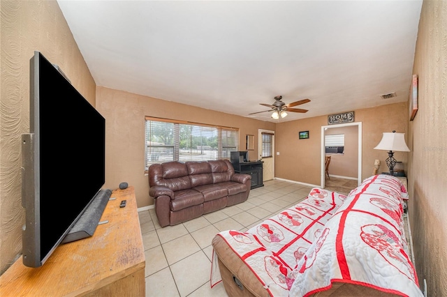 living area with baseboards, a ceiling fan, light tile patterned flooring, and visible vents
