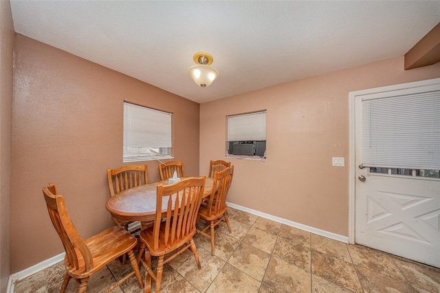 dining room featuring baseboards, stone finish floor, and cooling unit
