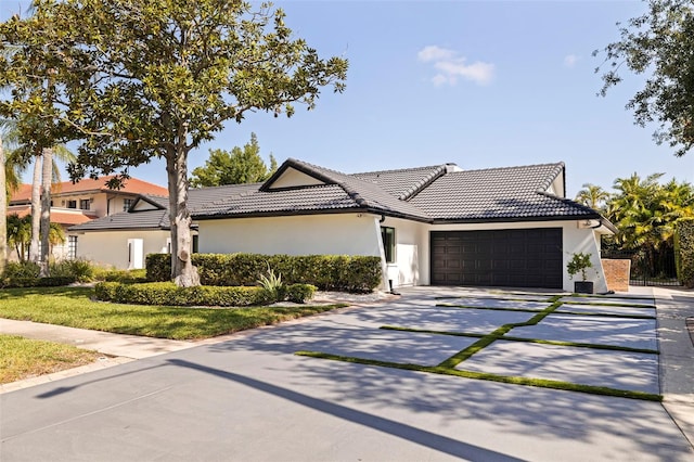 ranch-style house with an attached garage, stucco siding, a tiled roof, and concrete driveway