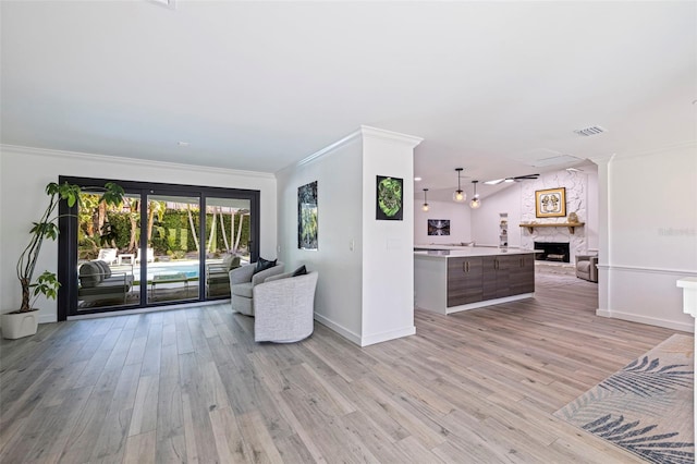 unfurnished living room with visible vents, crown molding, baseboards, light wood-type flooring, and a large fireplace