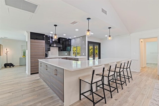 kitchen featuring crown molding, light countertops, light wood-style floors, and visible vents
