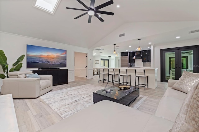 living area with wainscoting, french doors, a ceiling fan, light wood-type flooring, and visible vents