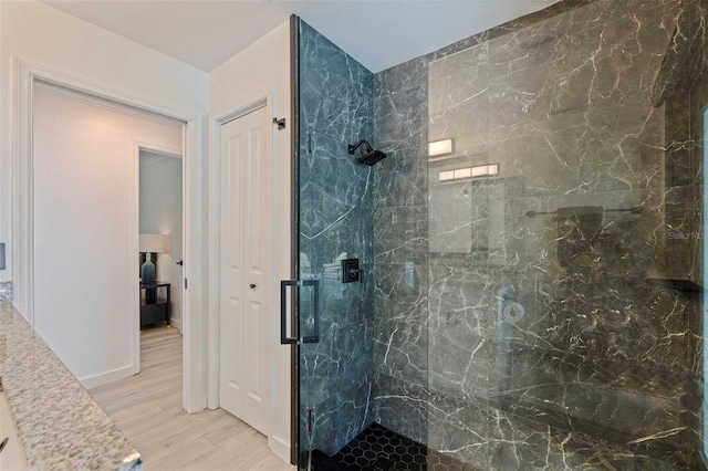 full bath featuring a marble finish shower and wood finished floors